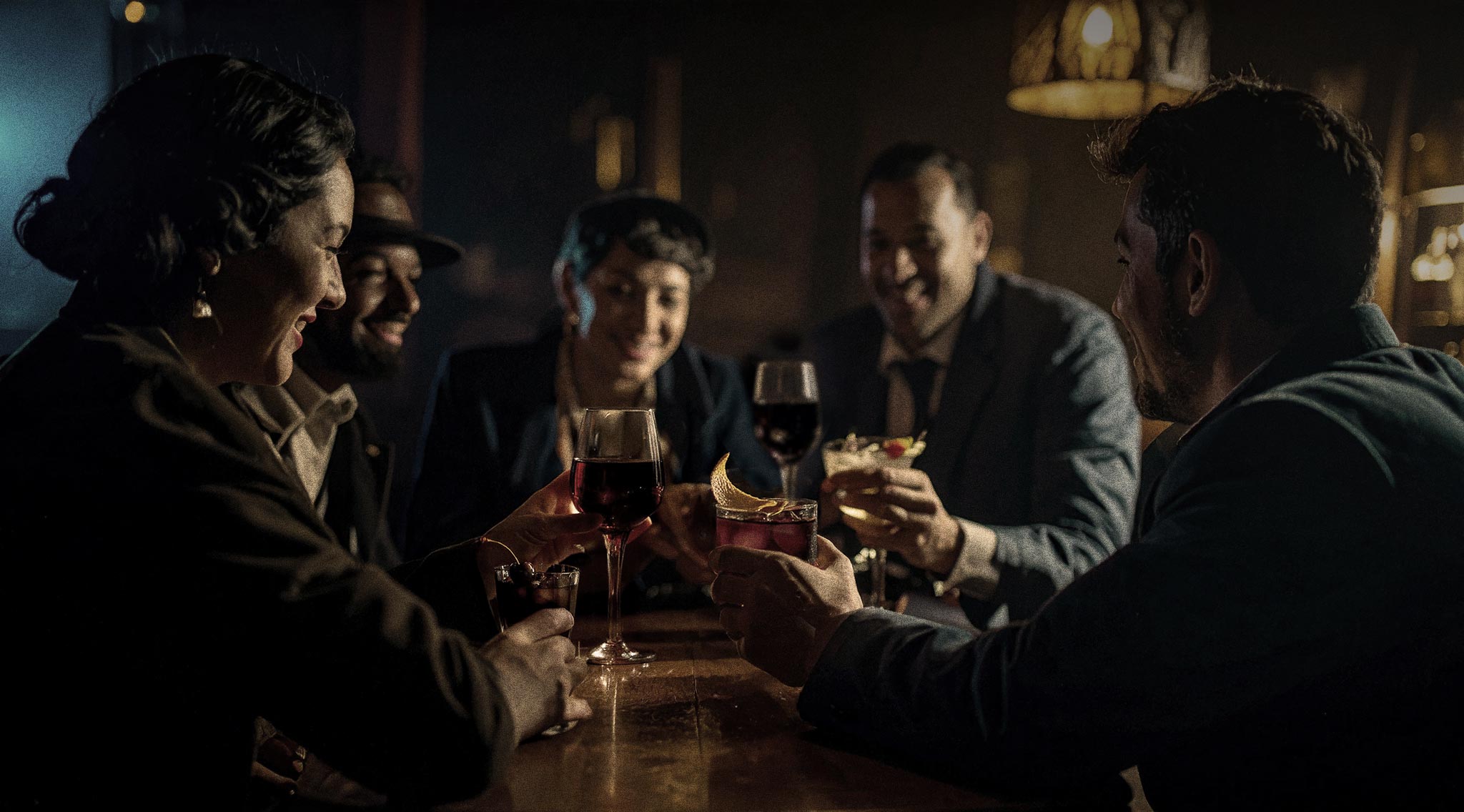 Image of people enjoying cocktails in a speakeasy style setting