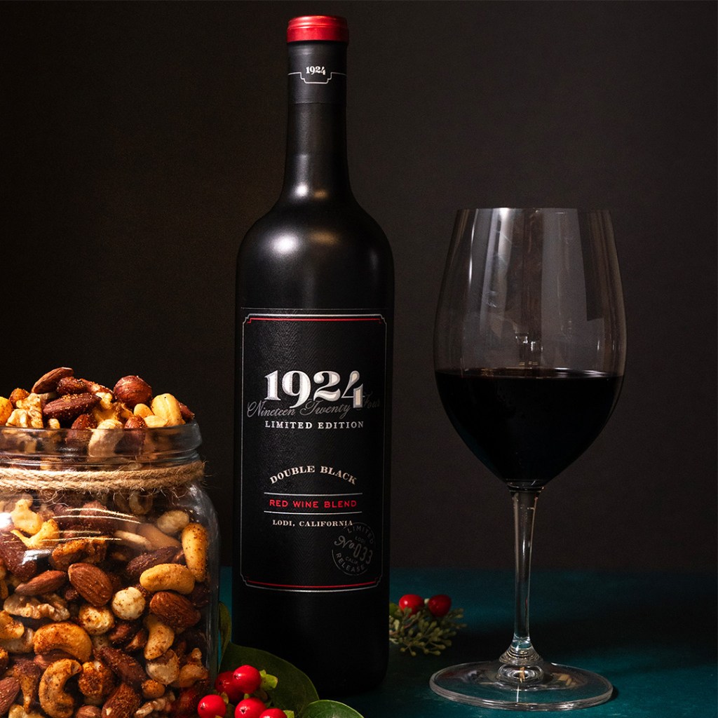 Photo of the 1924 Double Black Red Blend with a glass of wine and jar of mixed nuts