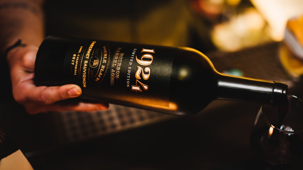 A bottle of 1924 Bourbon Barrel Aged Cabernet Sauvignon pouring into a wine glass.